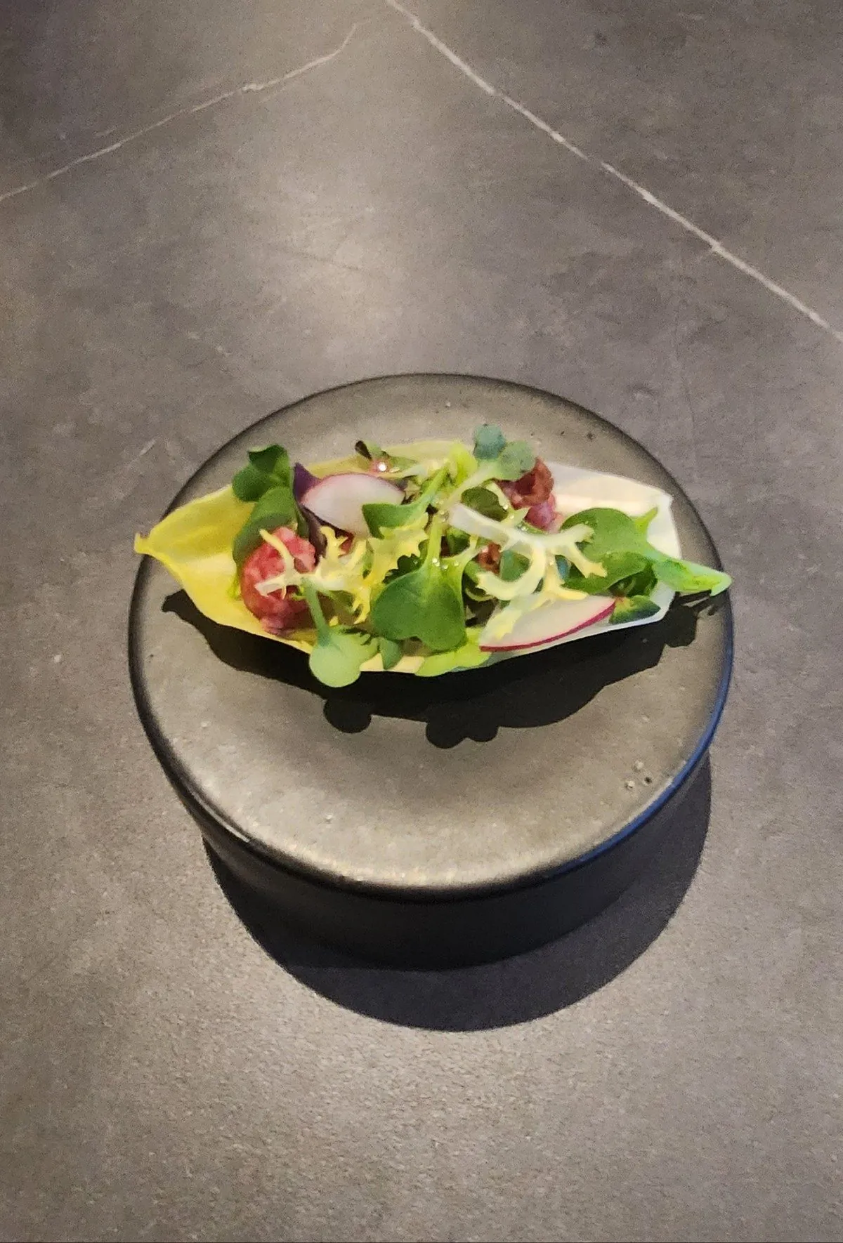 シトラスガーデン — KUT SEOULの韓牛カルパッチョ。柑橘ドレッシング、マイクログリーン、ラディッシュ、スライスオニオンを手作りの黒陶器プレートに盛り付け。